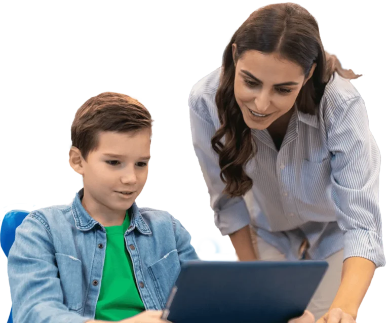 A teacher assisting a student with a laptop in a classroom setting,